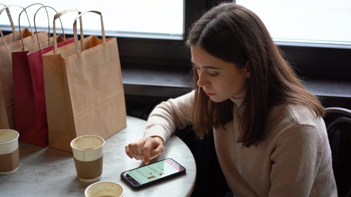 woman experiencing emotional spending triggers while scrolling shopping app alone at cafe