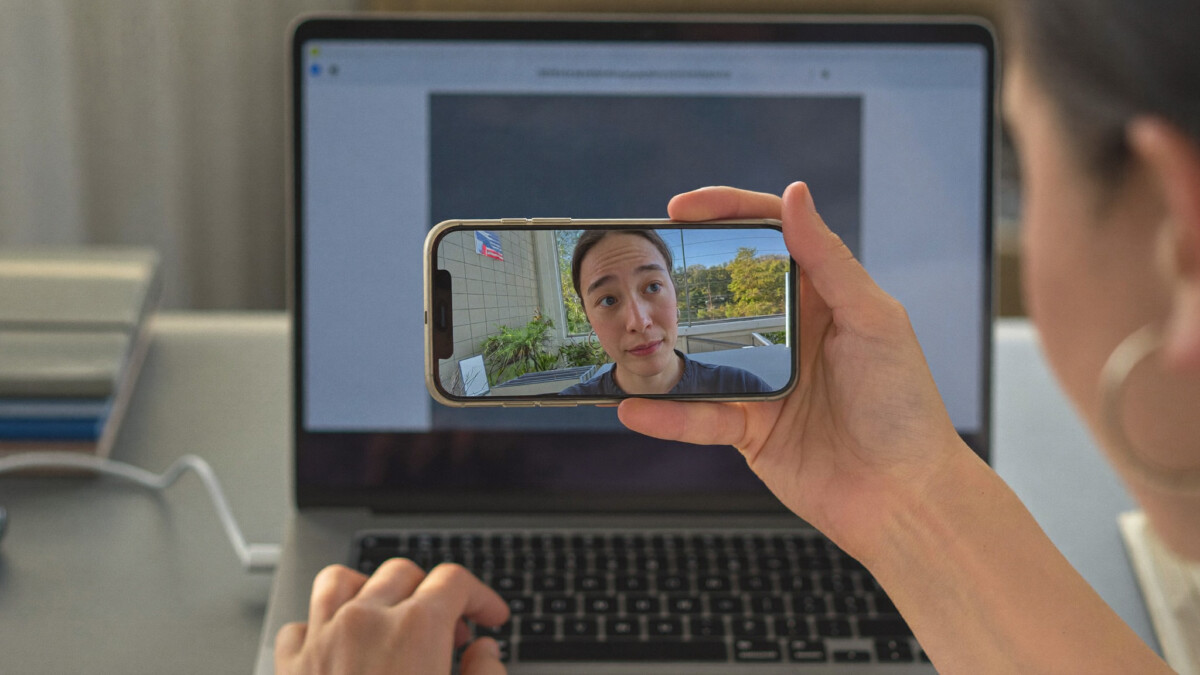 freelancer holding a phone face-down while sitting at a home office desk
